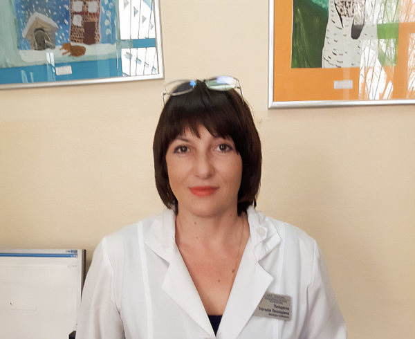 Doctor in white lab coat in office at her hospital.