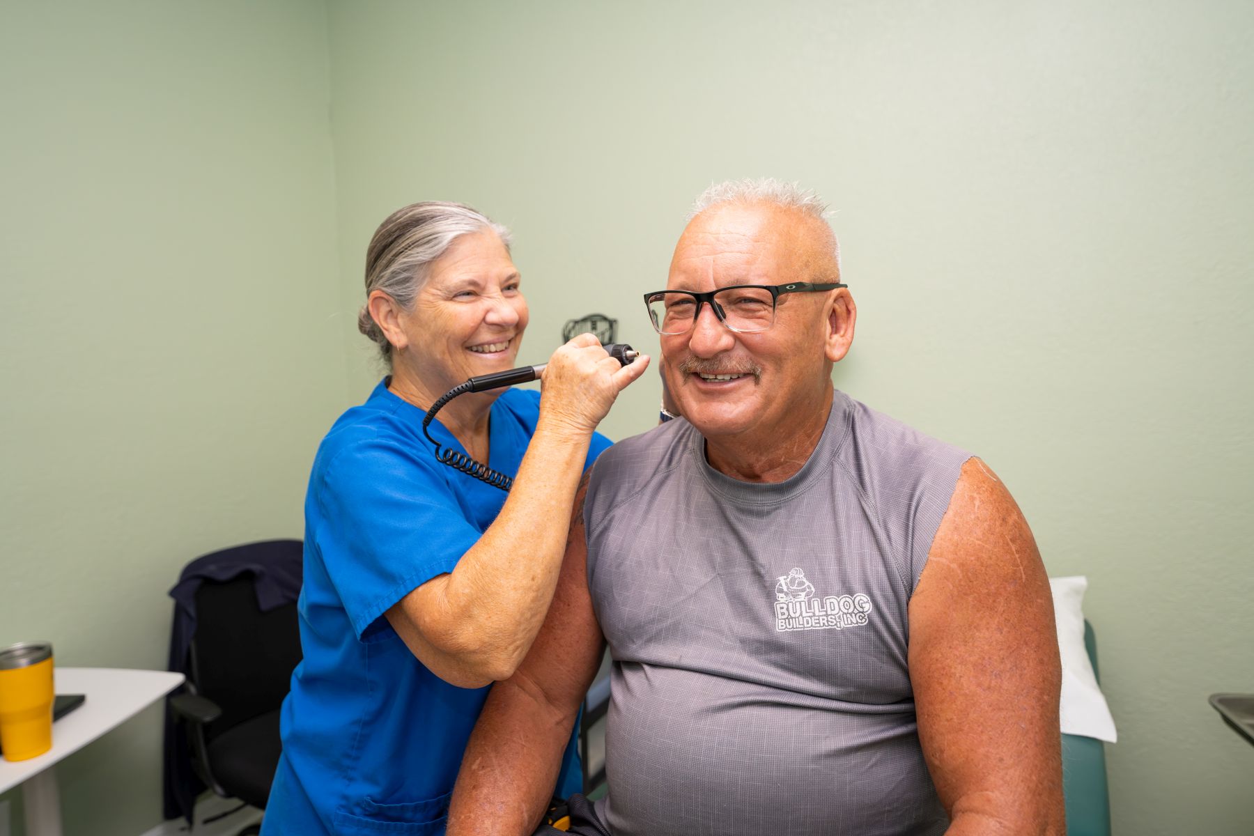 Doctor in blue scrubs doing an exam of a man in grey t-shirt