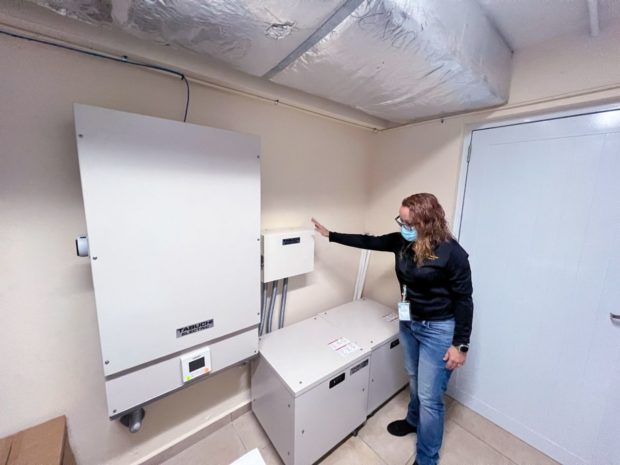 Administrator in blue shirt and jeans pointing out power panels inside clinic