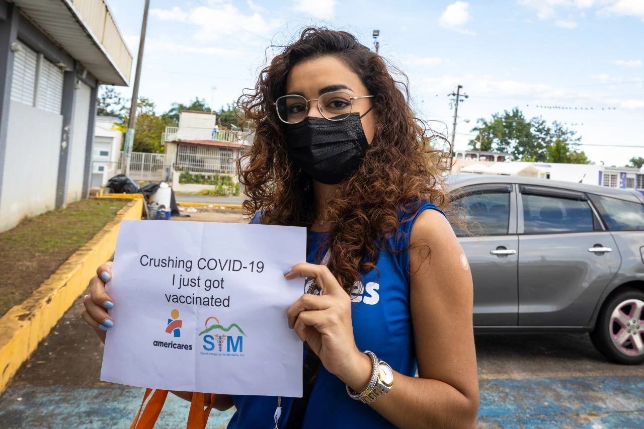 Americares staff member holds sign announcing that she has been vaccinated. 