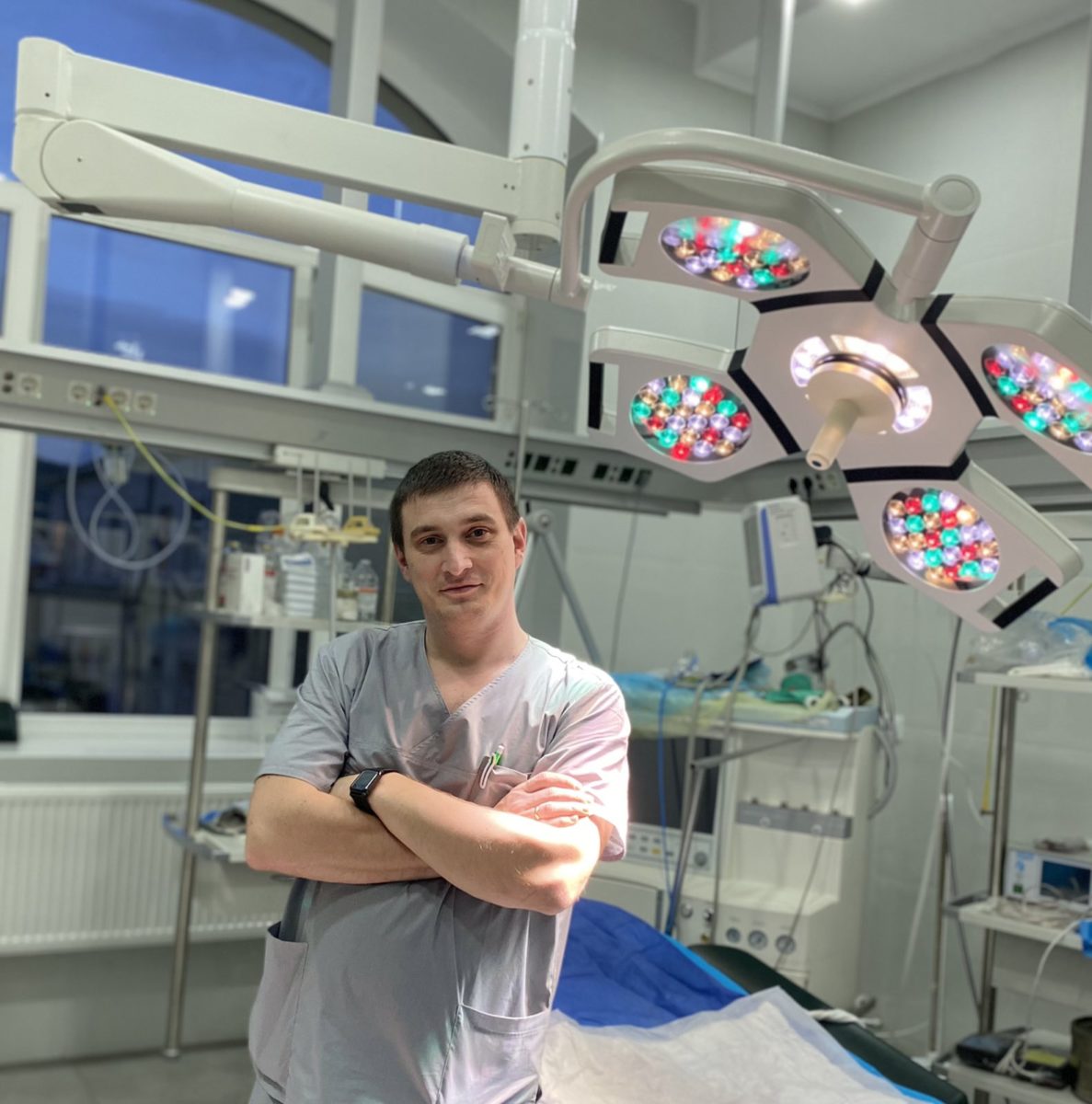 Doctor in operating room in scrubs with view of some of the equipment surrounding him.