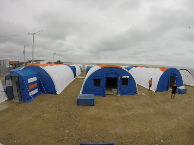 A handful of half-dome tents with cloudy skies above.